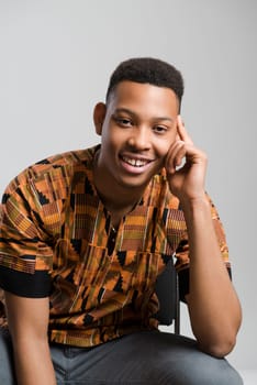 Portrait of handsome dark skinned male model smiling and wearing traditionally African clothes against white background