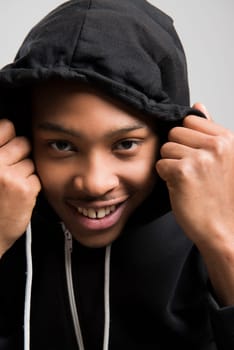 Portrait of handsome dark skinned male model wearing black hooded jumper