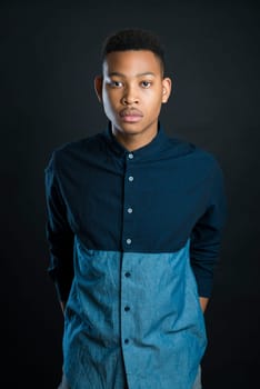 Portrait of handsome dark skinned male model wearing casual clothes against black background