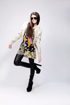 Happy young brunette woman with sun glasses against grey background, Fashion portrait