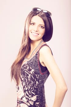 Happy young brunette woman with sun glasses against grey background, Fashion portrait
