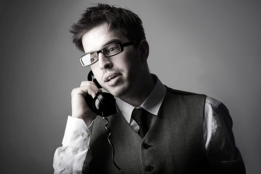 Young smart business man talking on the phone against grey background