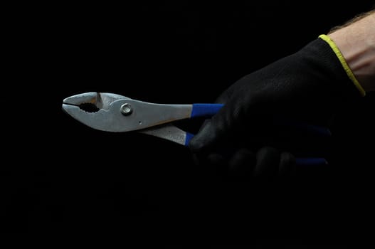 Pliers and a Hand on a Black Background