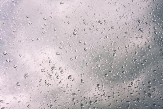 Water drops on window glass, blurred on the edges. Image processing with color filter effects