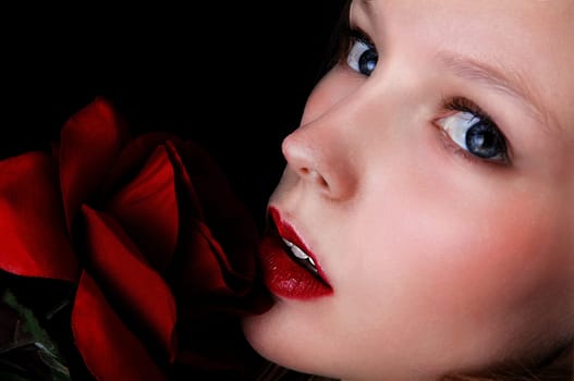A closeup picture of a lovely girls face with a red rose and blue eye's, .isolated on black background..