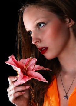 A lovely closeup picture of a beautiful teenager girl holding a pink lily.isolated for black background..