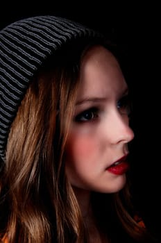 A profile portrait picture of a teenage girl wearing a knitted hat, .isolated for black background..
