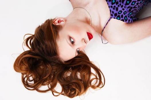 A pretty blond woman with long curly hair lying on the floor, isolated.for white background..