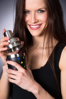 Bright eyed woman bartender mixes a martini in aluminum tumbler