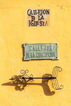 Streets signs on a yellow wall in the historic center of Mompox, Colombia