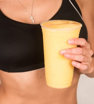 Woman holds Yellow Banana Fruit Smoothie Waist Level Showing Healthy Slender Body