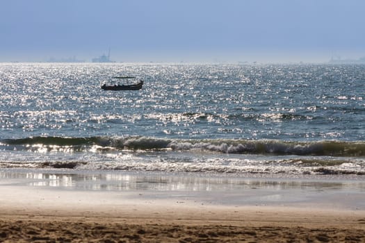 Boats at Arabian sea. Cargo ships on the background. View from beach in Goa, India