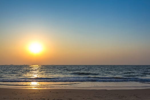 Scenic view from sand beach in Goa to beautiful sunset above the Arabian sea. Sun reflection on sea surface