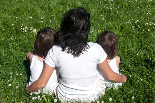 Mother with two children sitting back on spring meadow