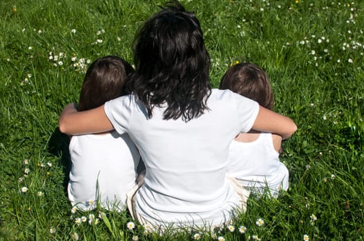Mother with two children sitting back on spring meadow