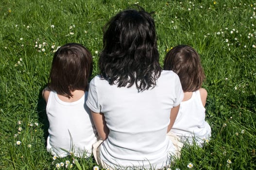 Mother with two children sitting back on spring meadow
