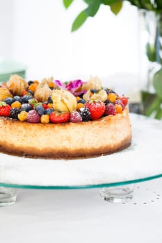 Closeup of delicious sponge cake topped with fresh berries on glass serving tray