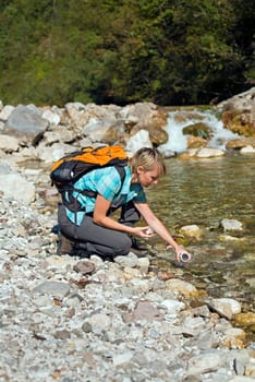 Hiker with backpack filling bottle of water