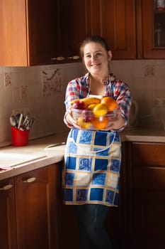 Portrait of happy housewife eating cucumbers from salad