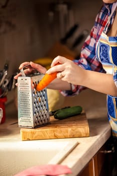 Closeup photo of woman grating carrot on wooden board