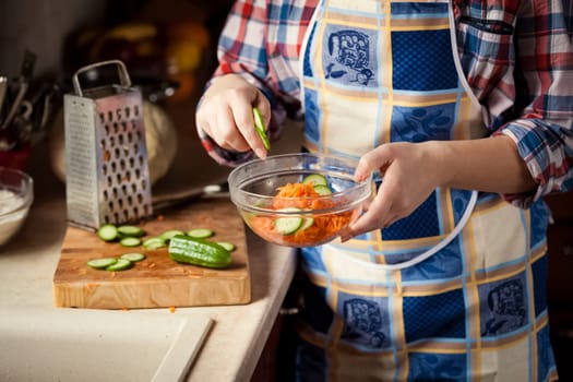 Closeup photo of woman mixing salad in glass bowl