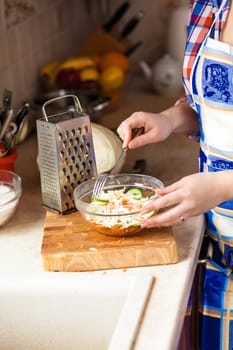 Closeup photo of woman eating salad with fork on kitchen