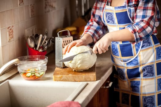 Closeup photo of woman cutting cabbage on kitchen