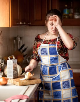 Brunette housewife crying while cutting onion