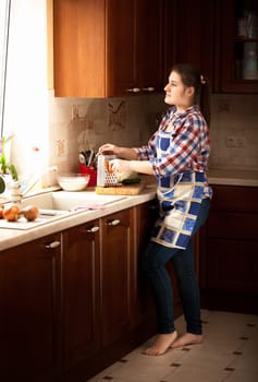 Young housewife working on classic wooden kitchen with big window