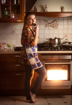 Beautiful housewife tasting chocolate cookie