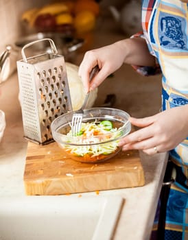 Closeup photo of housewife woman mixing salad with fork