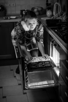 Black and white portrait of woman putting pan in oven