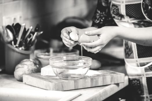 Black and white closeup photo of woman cracking egg