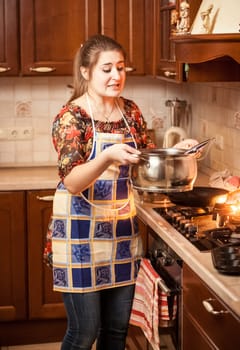 Portrait of beautiful woman carrying soup in metal saucepan