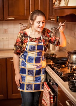 Closeup portrait of woman trying soup with ladle