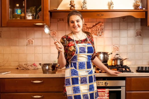 Portrait of beautiful housewife holding soup ladle on kitchen