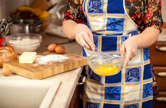 Closeup photo of woman whisking eggs in glass bowl