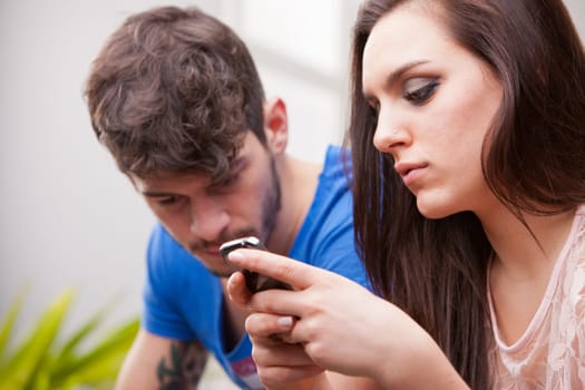 a young beautiful woman sending text messages with her mobile phone ignoring her very frustrated man