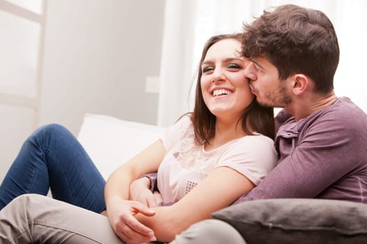 the man kisses the woman because he loves her and they love each other and hey are falling in love on a sofa in a living room
