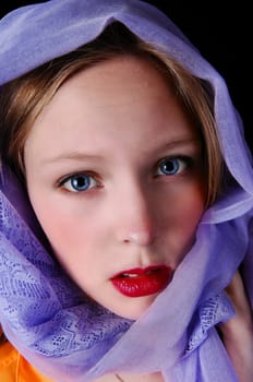 A beautiful young woman with blue eye's and a blue scarf around her.head, isolated for black background..