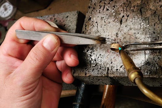 Skilled hands that create handmade jewelry with gold processing.