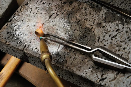 Skilled hands that create handmade jewelry with gold processing.