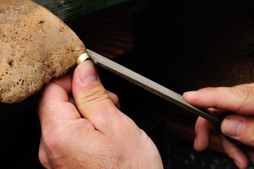 Skilled hands that create handmade jewelry with gold processing.