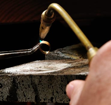 Skilled hands that create handmade jewelry with gold processing.