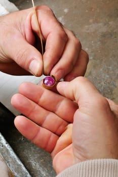 Skilled hands that create handmade jewelry with gold processing.