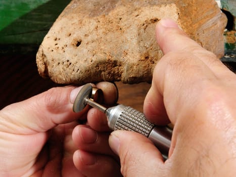 Skilled hands that create handmade jewelry with gold processing.