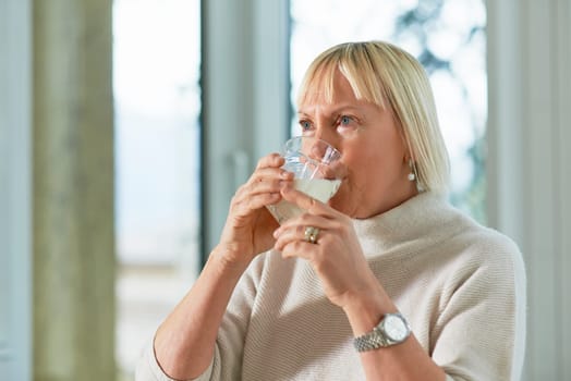 Portrait of senior caucasian woman drinking fresh milk for breakfast at home