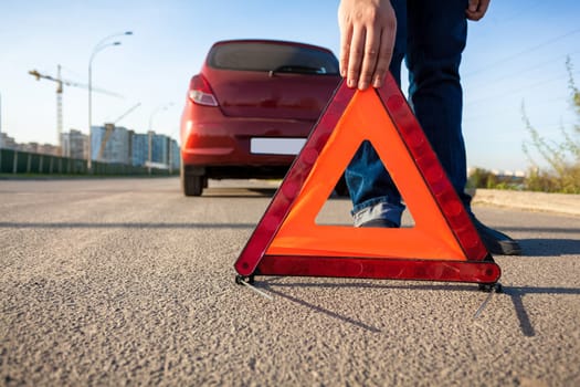 Closeup photo of man putting triangle warning sign on road