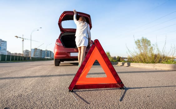 Photo of woman looking in trunk of broken car