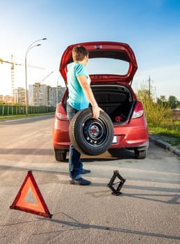 Photo of man taking spare wheel out of trunk